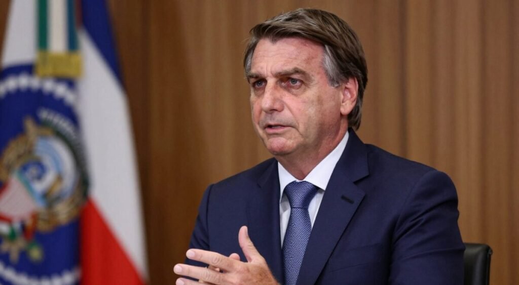 A portrait of Jair Bolsonaro in a professional setting, capturing him in a thoughtful pose as he engages in a discussion. He is dressed in a tailored navy blue suit with a crisp white shirt and a subtle patterned tie, symbolizing leadership and authority. The background features a blurred official setting, hinting at government elements such as flags or an emblem to suggest his political stature. Soft, warm lighting enhances his features, casting gentle shadows that evoke a serious yet approachable demeanor. The image reflects a mood of contemplation and concern, emphasizing the impact of family values in his public image. The angle is slight, presenting him from a three-quarter view to add depth to the composition.